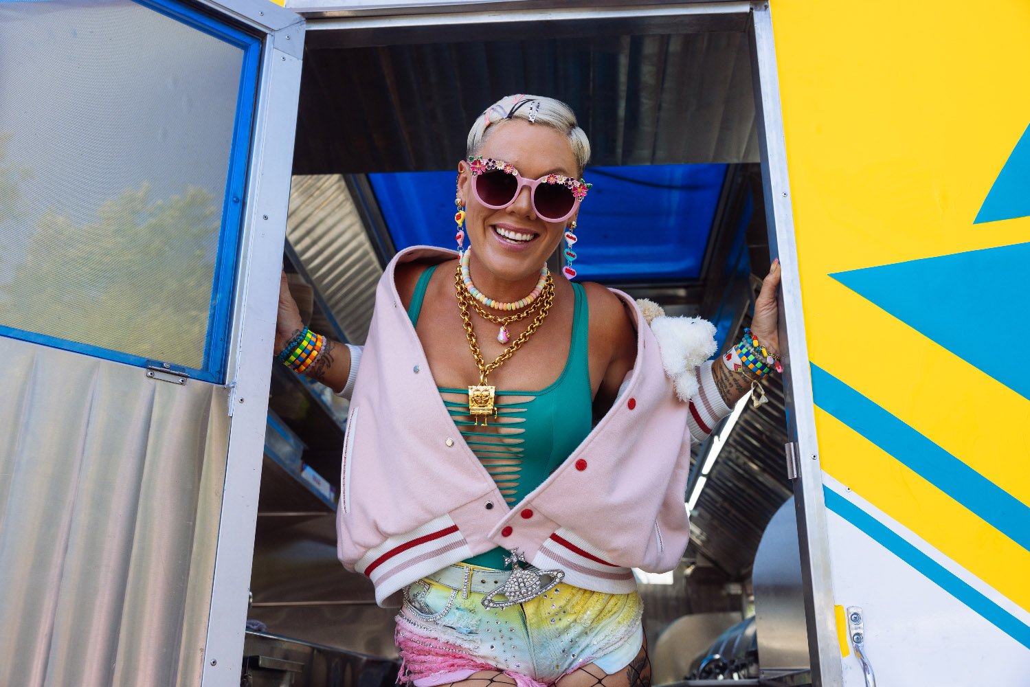 Pink smiling as she stands in the doorway of a tour bus.