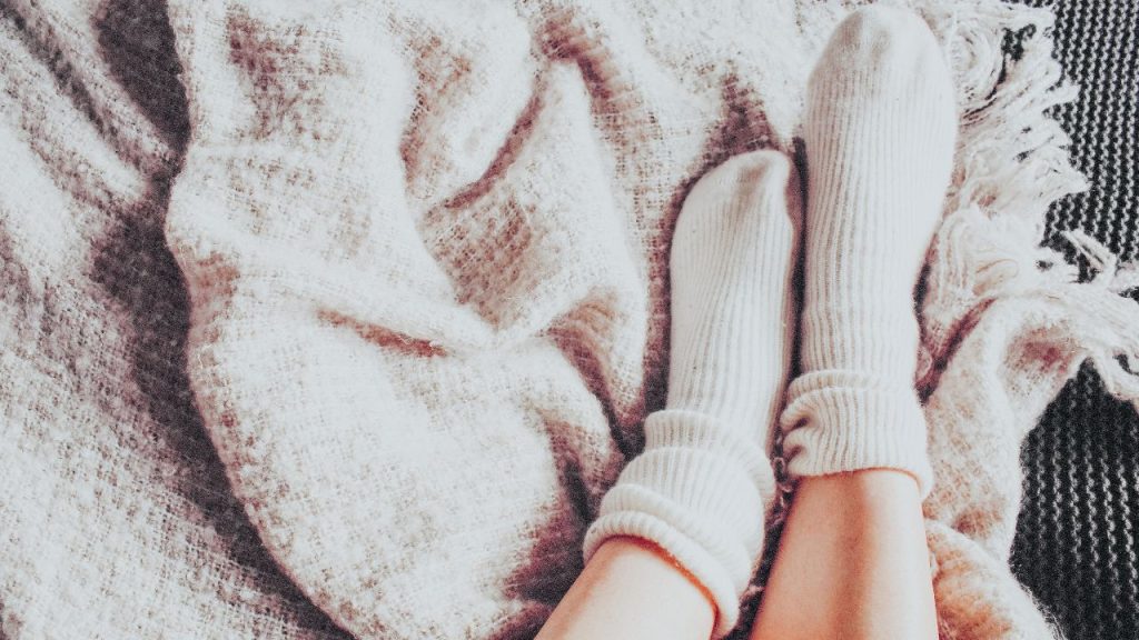 Image of a persons fluffy socks and a blanket. 