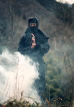 A ninja standing (appearing?) in a cloud of smoke in a field