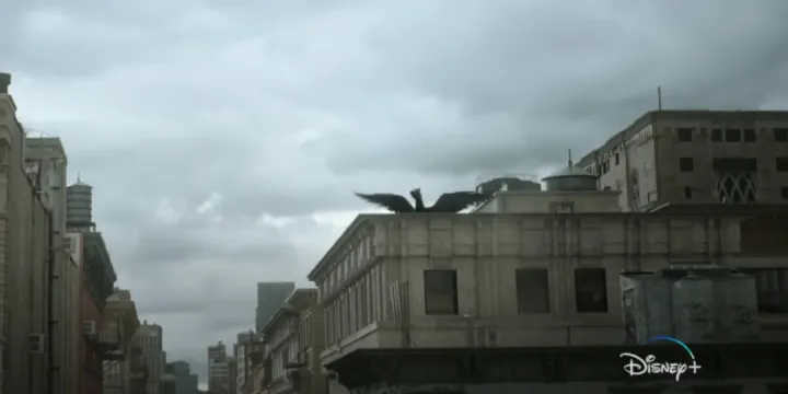 A black pegasus on the roof of a large building that is surrounded by other tall buildings.