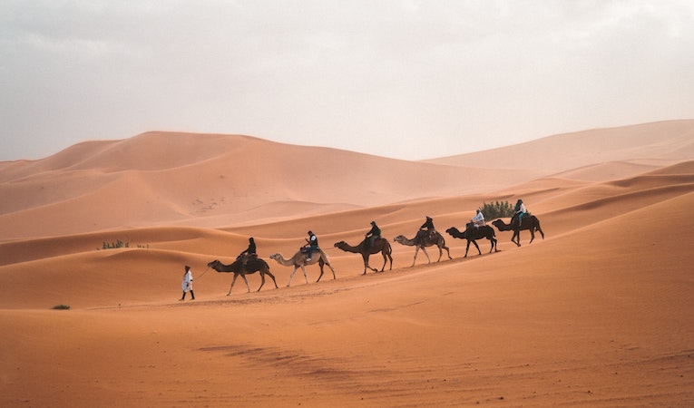 Arab Desert with six people riding camels 