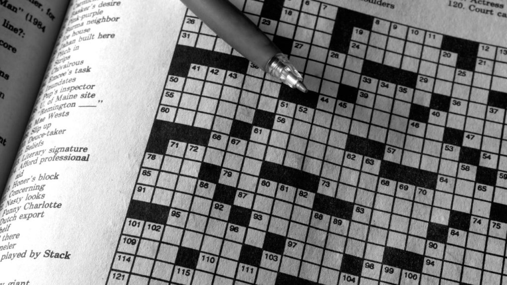 A crossword puzzle with a pen lying across it.