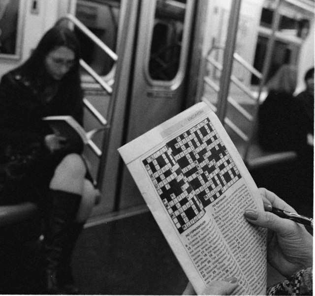 A woman solving a crossword puzzle on a New York subway car. 