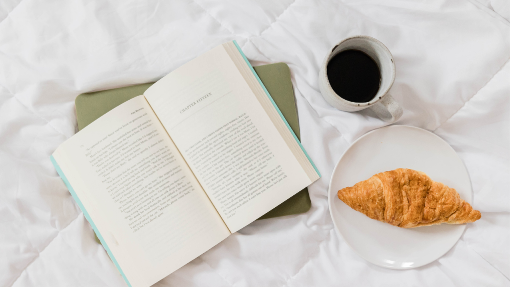 Food and drink in bed with book.
