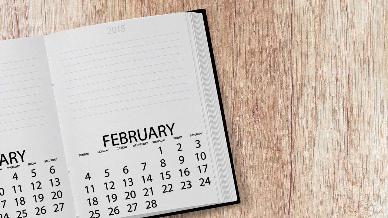 A calendar book that is opened to February sitting on a wooden table