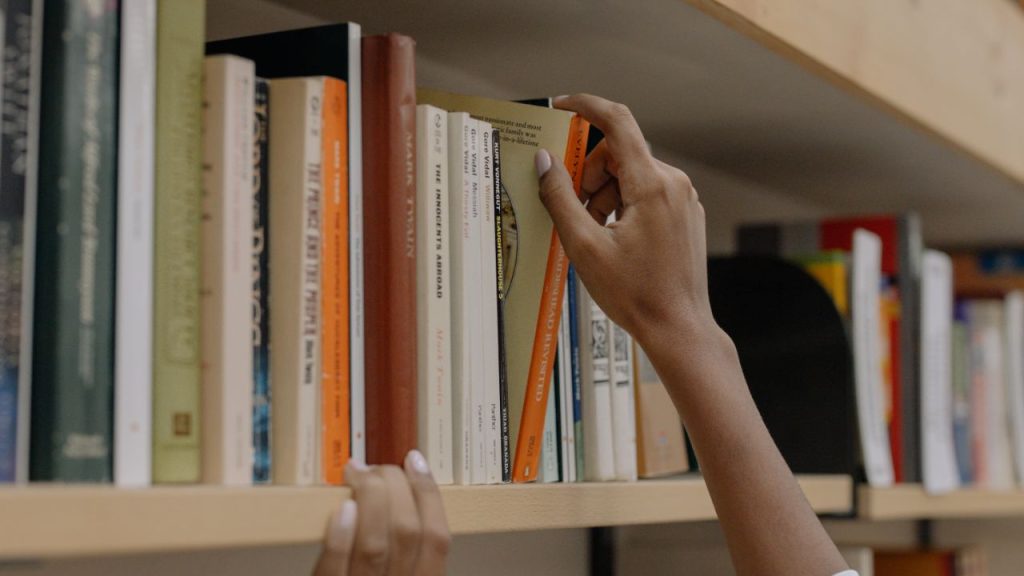hands pulling a book from a shelf