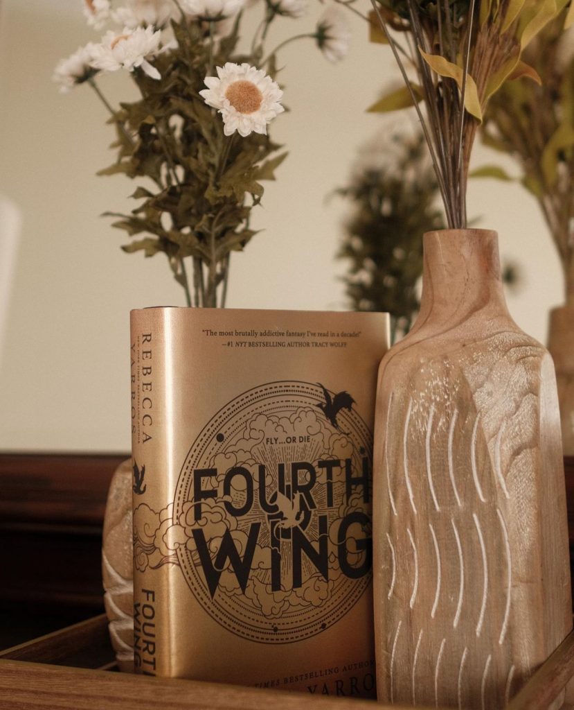 "Fourth Wing" book places in between two flower vases.
