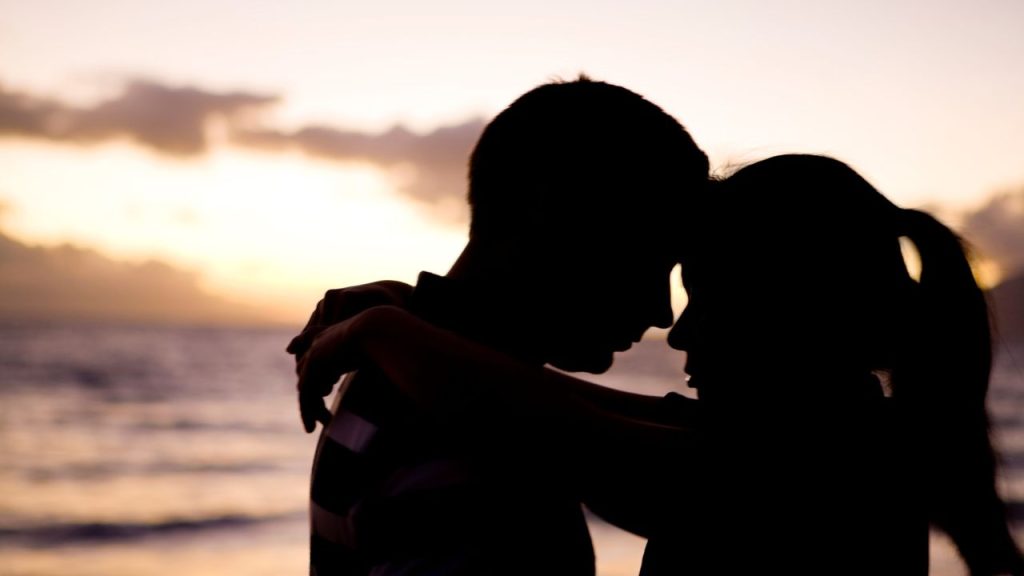 Silhouette of a couple holding each other at the beach.