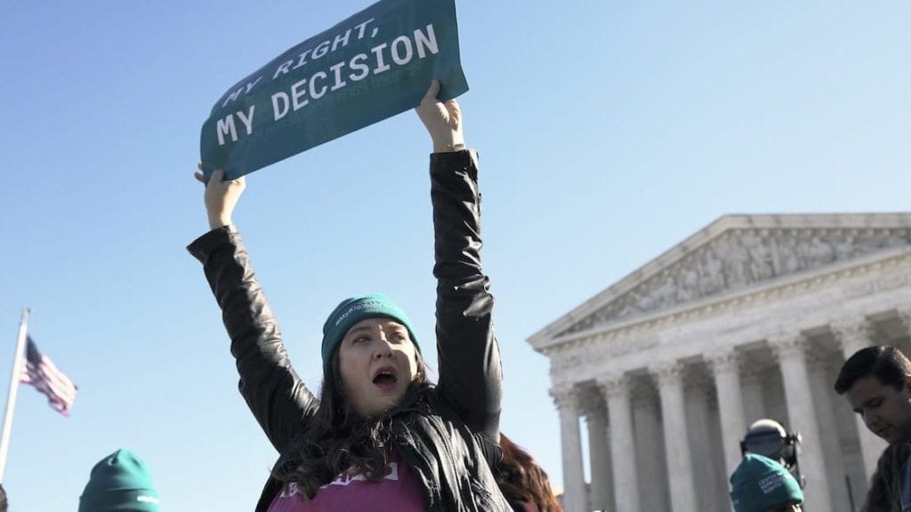 A woman holding up a sign that says "My right, my decision."