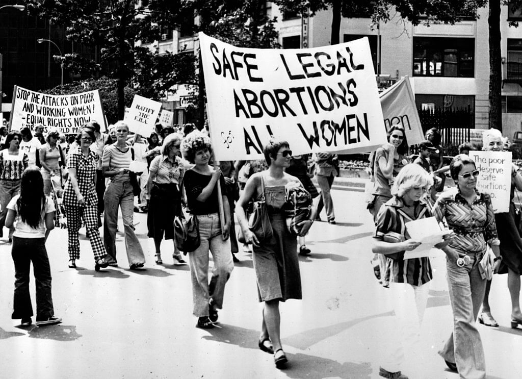 Women marching with signs such as "Safe legal abortions all women."