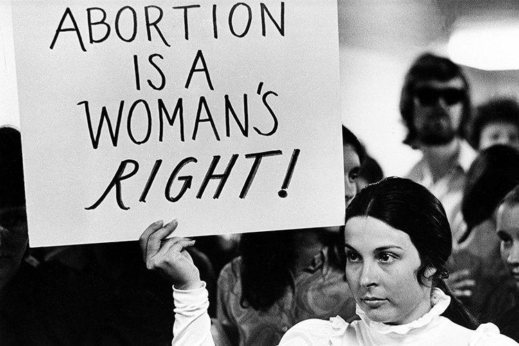 A woman holding a sign that says "Abortion is a woman's right" during a protest in 1971.