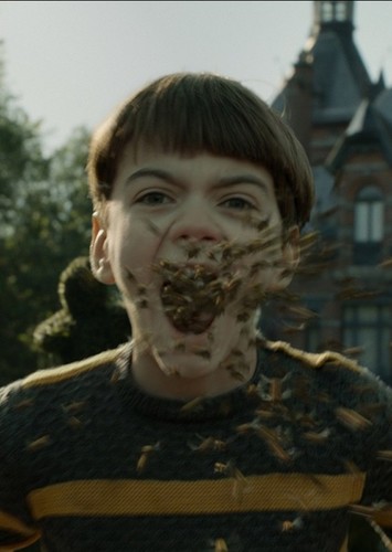 A boy with brown hair and a yellow-striped sweater with bees coming out of his mouth.