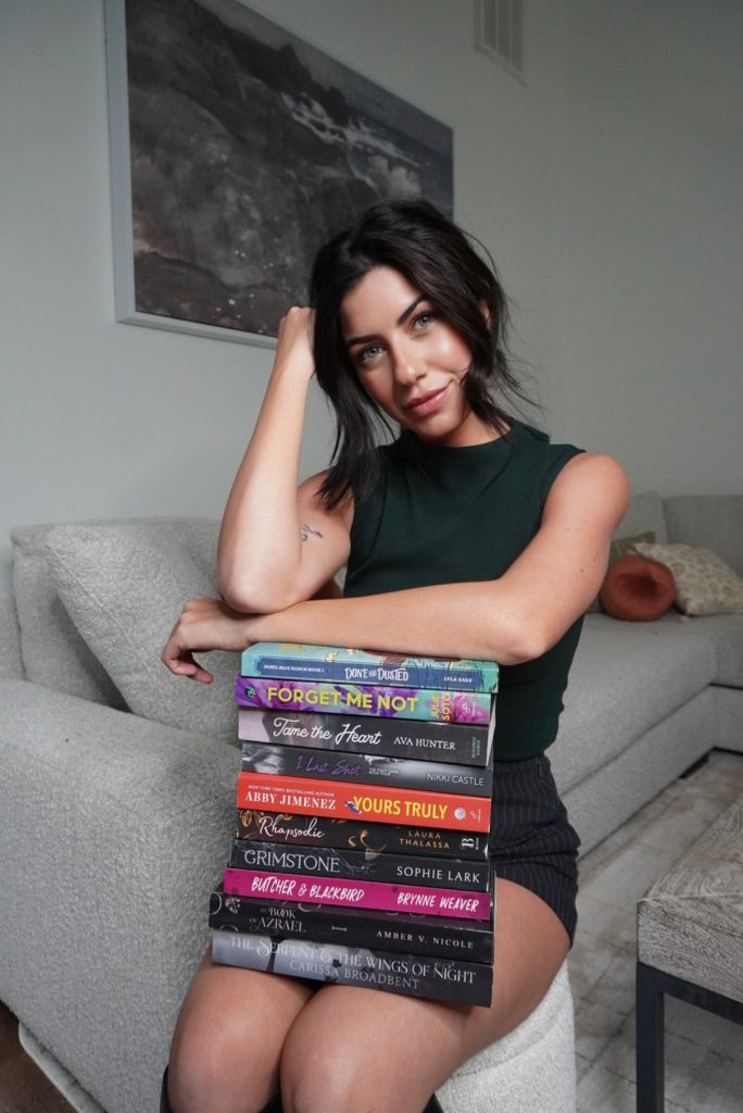 Halle sitting on a couch with a stack of books in her lap