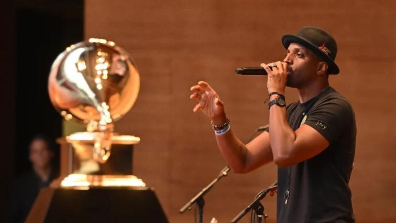 J. Ivy speaking into microphone with Grammy award to the side