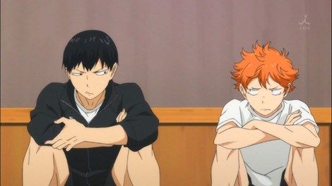 Hinata and Kageyama sitting on the floor side-eyeing each other.