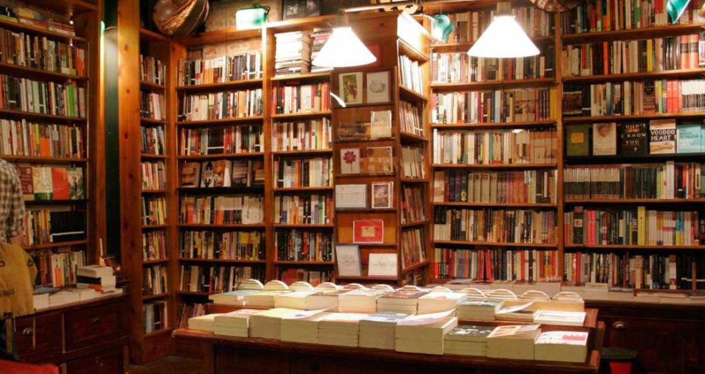A bookstore with bookcases and tables full of books.