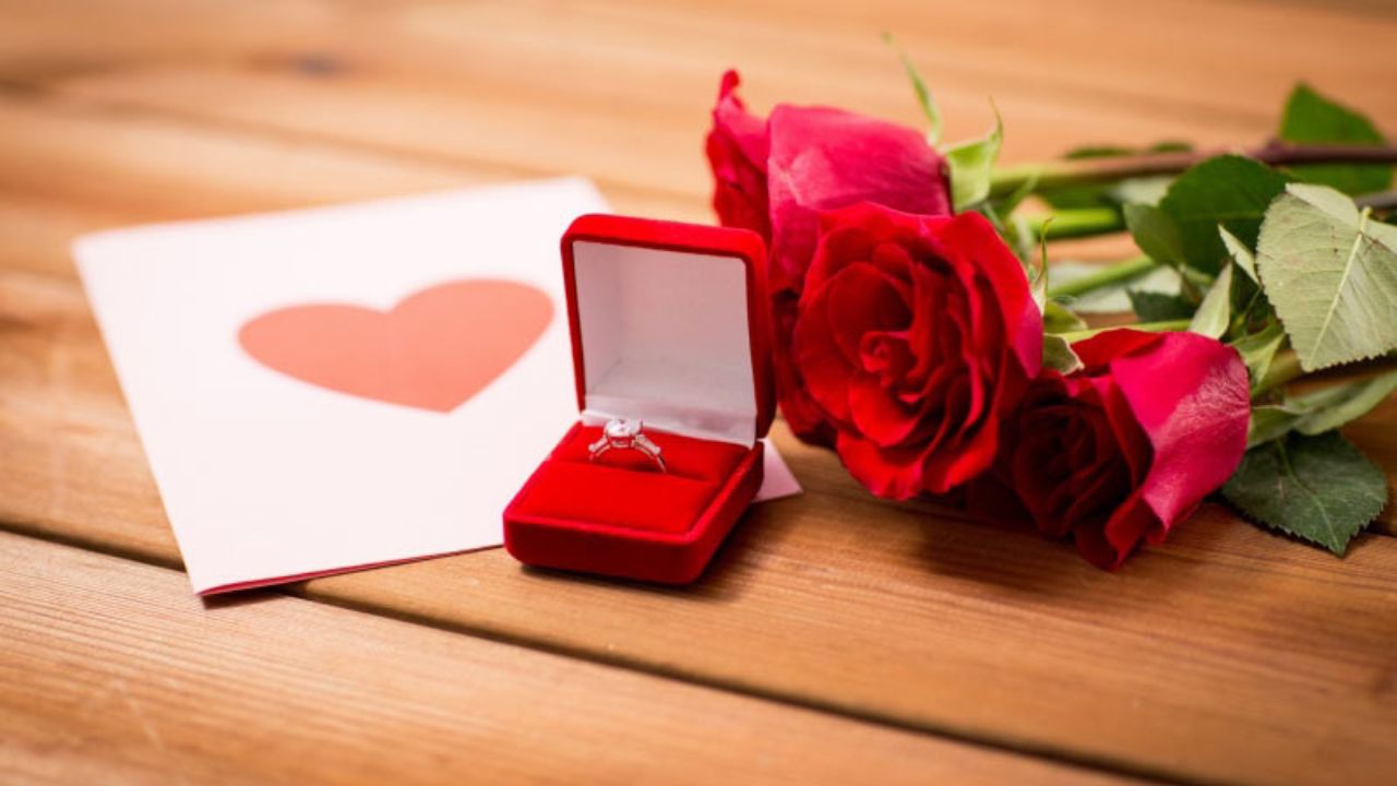 Red roses, a ring in a box, and a card with a heart on it.