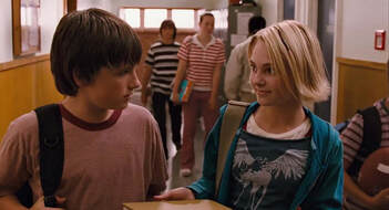 Jesse and Leslie talking in a school hallway.