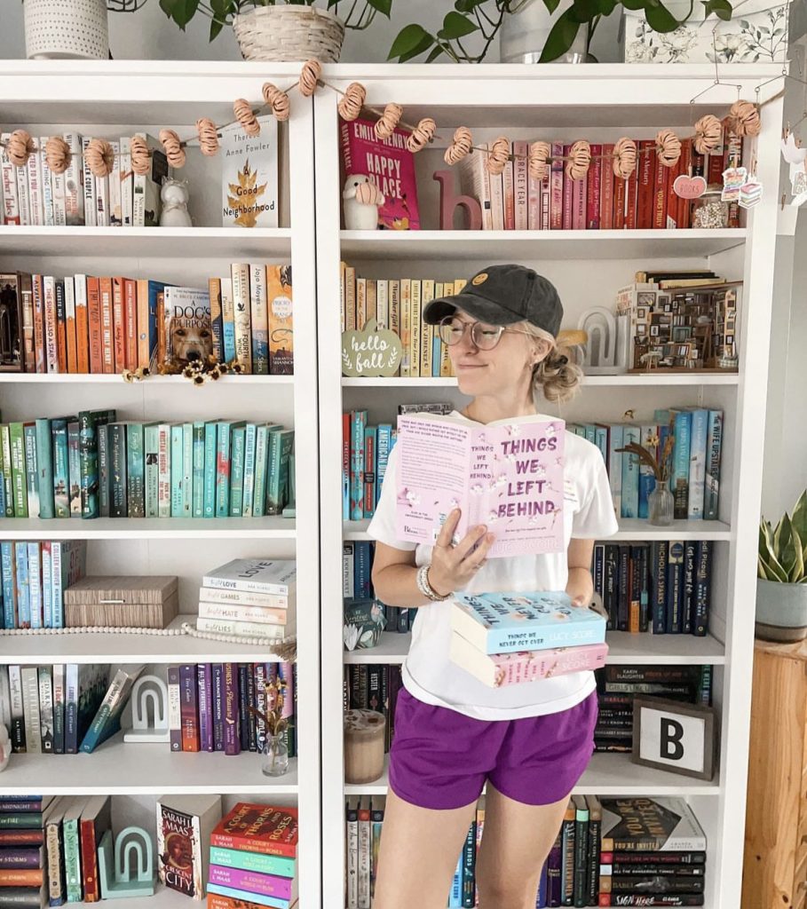 Jacyln holding Lucy Score's Knockemout series in front of her bookshelves