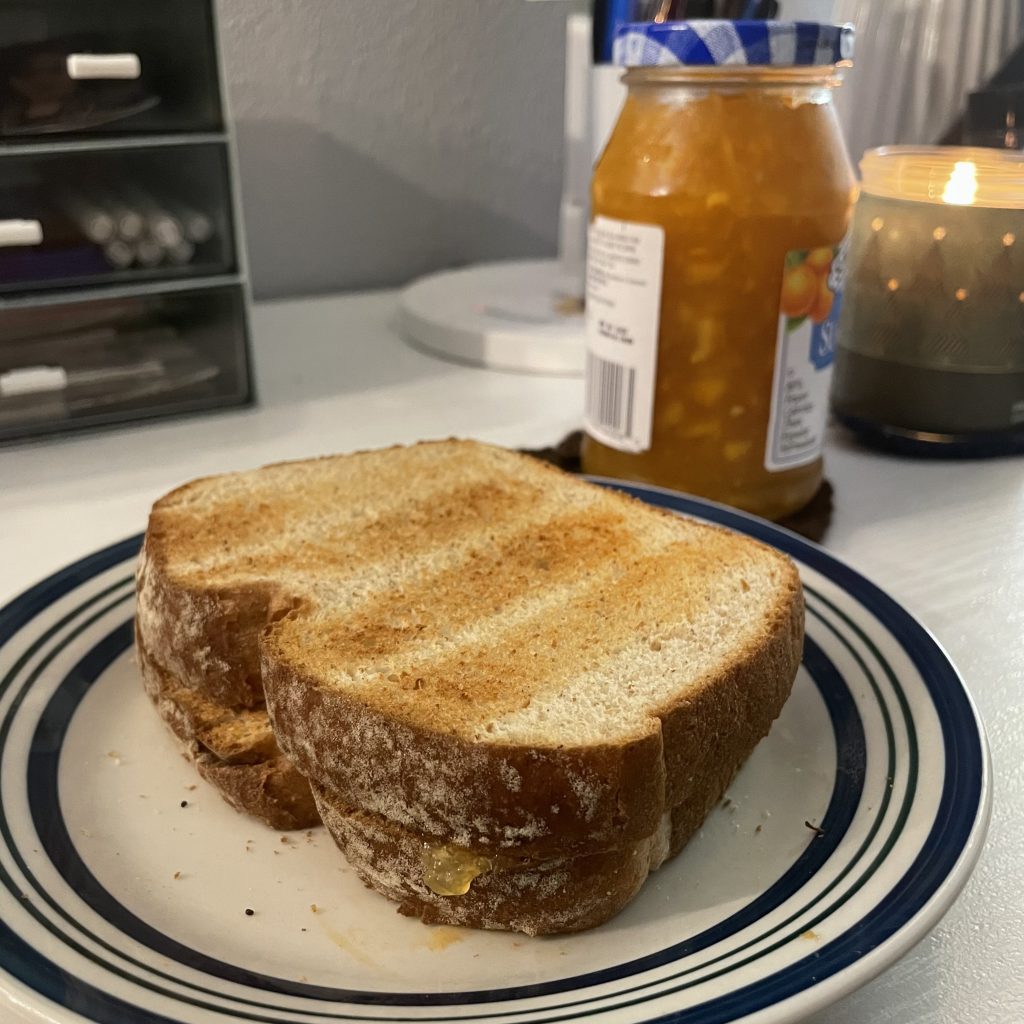 There is a plate of toast filled with marmalade, with a can of marmalade behind the plate.