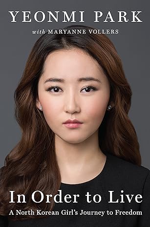 classy gray background and a portrait of a young Korean woman with long brunette hair, wearing a plain black shirt and diamond earrings and cosmetics. Across the top in white font it says: Yeonmi Park with Maryanne Vollers. Across the bottom in the same white text it says: In Order to Live A North Korean Girl's Journey to Freedom.