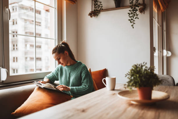 woman reading at a table and couch before a window