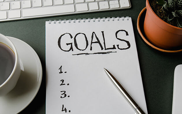 note pad with goals an a list on a desktop