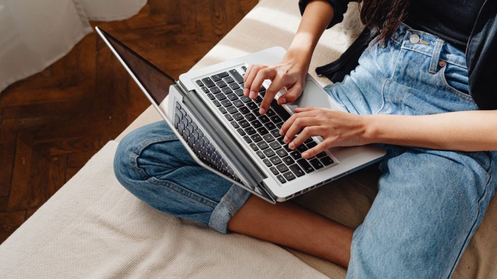 woman laying down and typing on a laptop