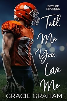 Fuzzy background of a playing field with stadium lights on. In the forefront on the left hand side is a football player wearing an orange jersey and helmet and dark blue pants, holding a football in his gloved right hand. Along the right hand side of the book cover is the title, written in white handwriting font: Boys of Riverside Tell Me You Love Me. Along the bottom of the cover, in white lettering, is the authors name: Gracie Graham.