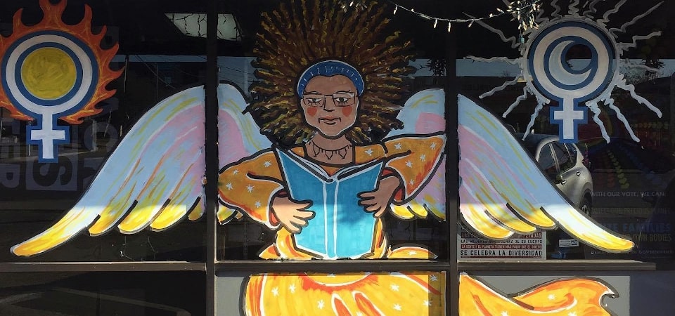 Artwork on the storefront of Bookwoman showing an angelic woman reading a book.
