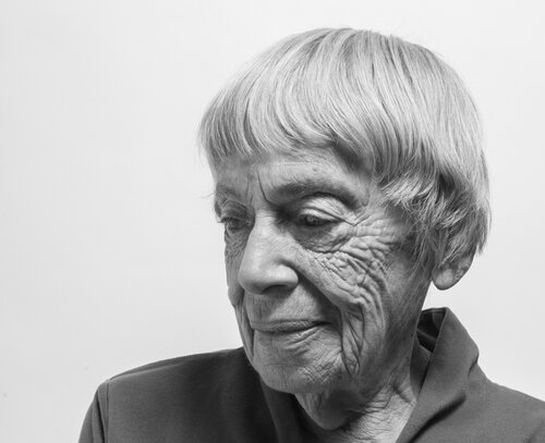 A black and white photo of Ursula K. Le Guin looking down.