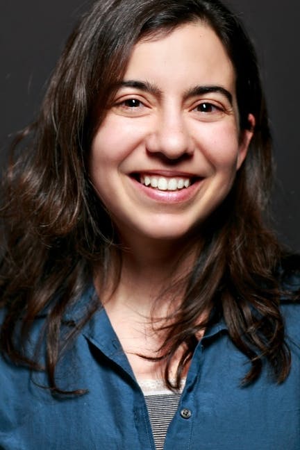 headshot of author Malka Older in a blue shirt and a grey background