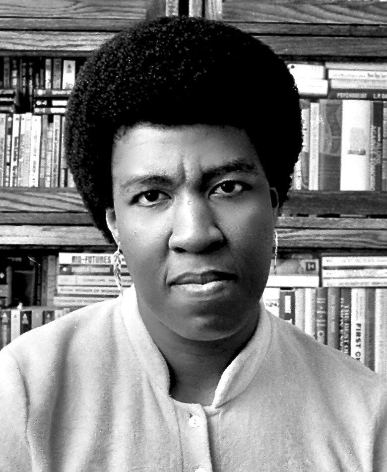 black and white image of octavia butler in front of a bookshelf