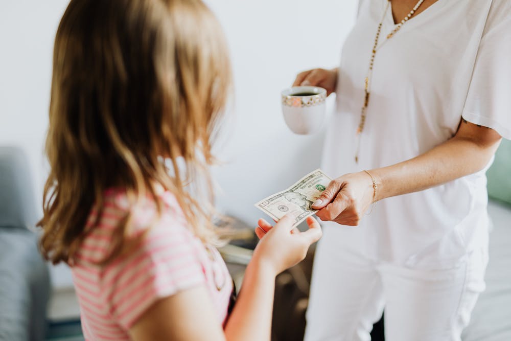 A person giving a young child money.