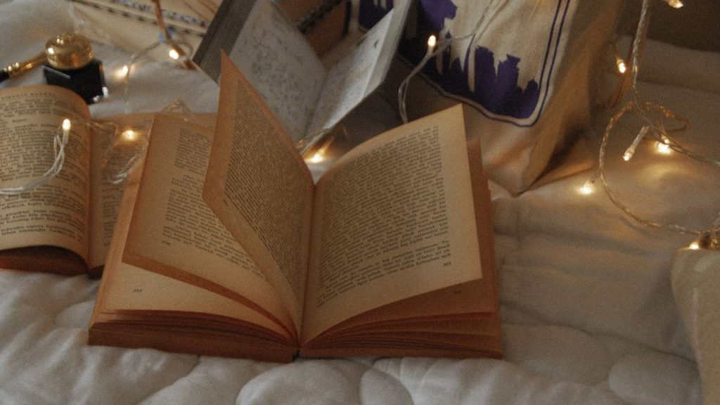 Opened book on a blanket with fairy lights around