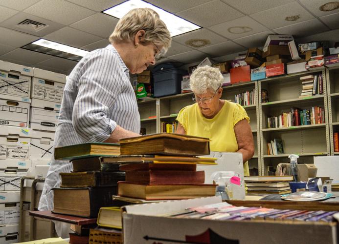 Two women looking over a table with books.