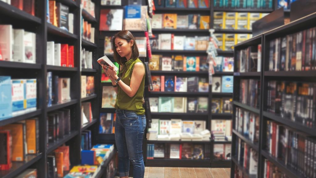 A woman standing in a store with books all around her.