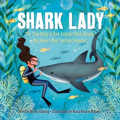 A woman in a diving suit with an oxygen tank touches a nose of a shark against an underwater background.