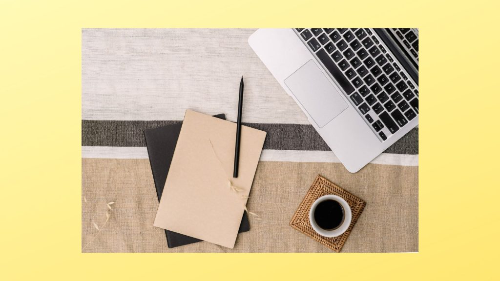 Image of a notebook, pen, coffee cup, and laptop on a yellow background.