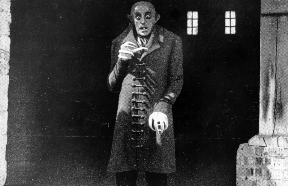 an image of nosferatu, a bald, corpse-like, animalistic figure with unnervingly elongated fingers.