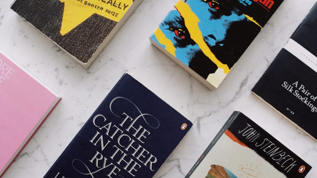 Different books arranged diagonally across a white marble table.
