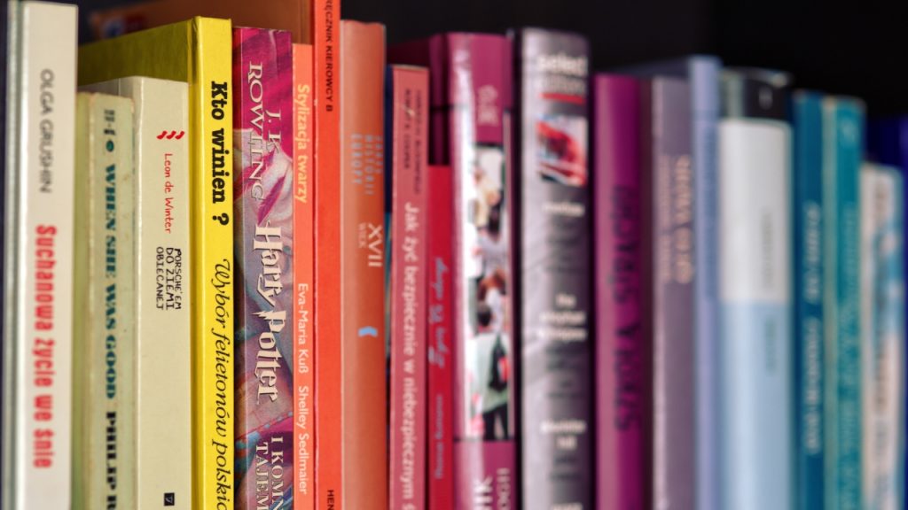 A stack of vertically stored books with colorful spines.