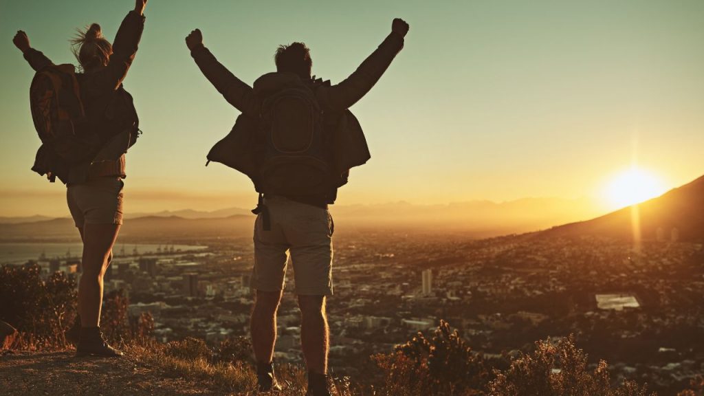 A man and woman spreading their arms out and celebrating their hike accomplishment.