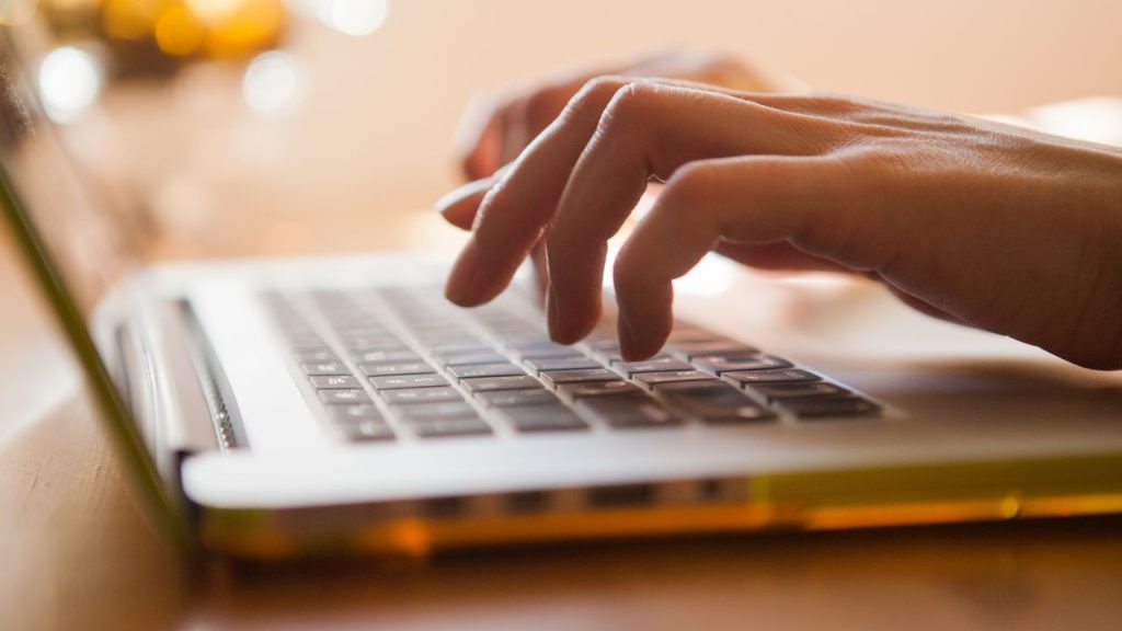 Fingers typing and hovering over the keyboard.