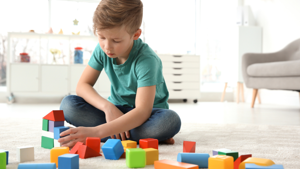 A little boy playing with a wide variety of colored blocks