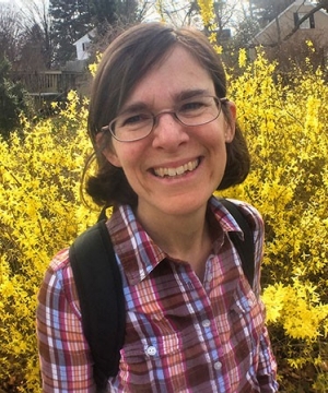 Cece Bell smiling with a brightly colored bush in the background.