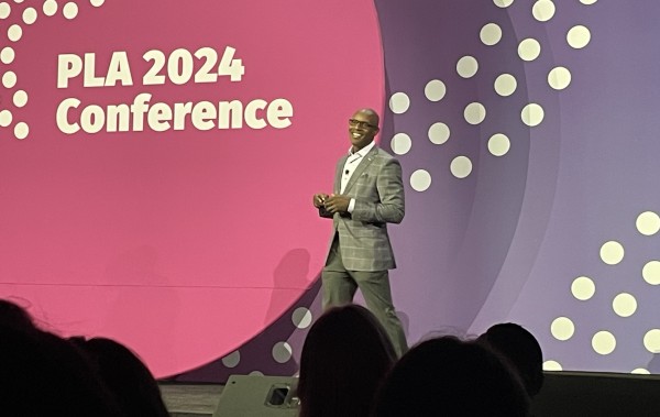 Author Shola Richards delivering keynote speech to attendees at 2024 Public Library Association conference.