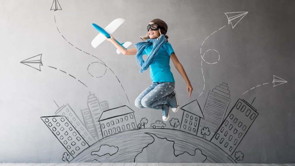 An adventurous kid playing and jumping in mid-flight with a toy plane.