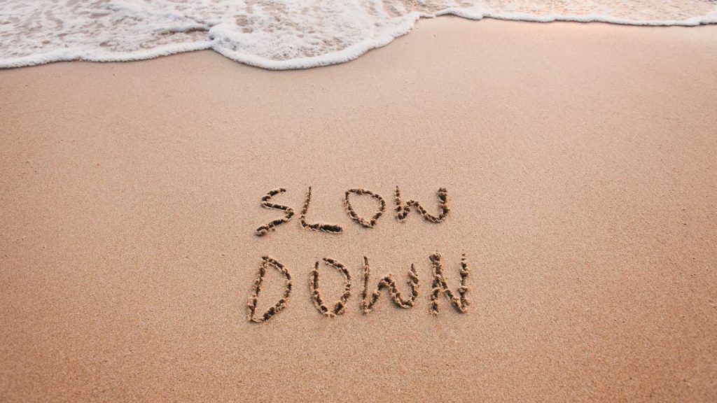 slow down carved in the sand of a beach.