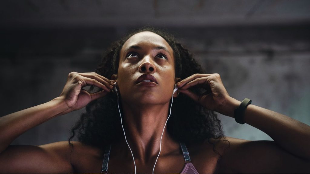 A woman placing earbuds into her ears, ready to start on her run.